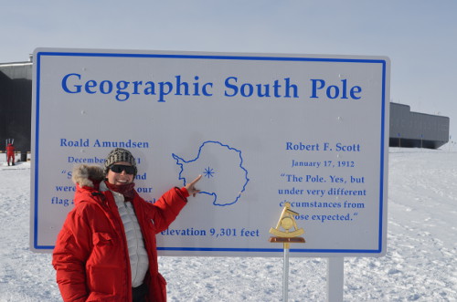 Michelle Brown points to the Geographic South Pole. This is the Geographic South Pole as measured in January of 2011. Amundsen–Scott South Pole Station, Antarctica.  Photo by Andy Stillinger, Courtesy of Michelle Brown (PolarTREC 2011/2012), Courtesy of ARCUS