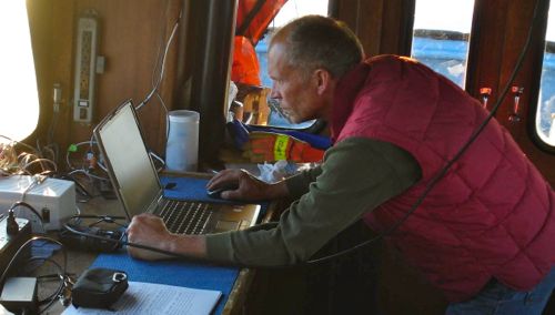 Steve downloads the data from his CTD. The CTD records the data internally. At the end of the day, he hooks the instrument up to a computer via a long cable and downloads the data.  Here he is working on the lab counter in the cabin of the Annika Marie. Photo courtesy Dr. Carin Ashjian.  August 2014