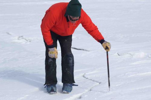 Ned uses an icepick to test the thickness of the ice