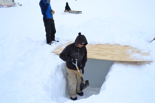Lance digging a backlit snow pit