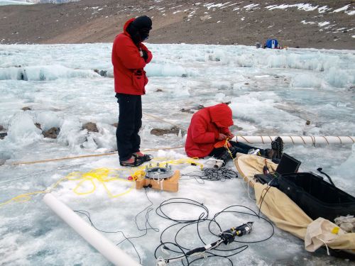 Sasha and Justin adjusting sediment trap.  Drill hole is in foreground with drop camera and computer nearby.