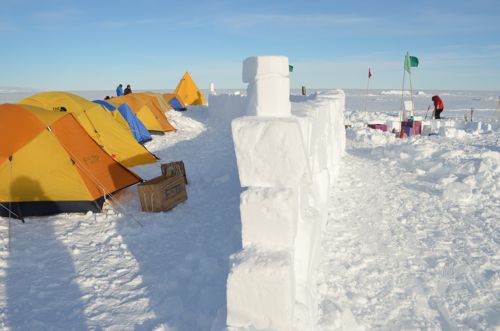 A snow wall separates the tents from the kitchen
