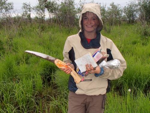 Dylan returns from soil sampling with her soil saw, field notebook, and samples.