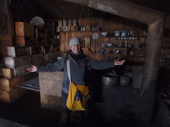 Amy Osborne stands in front a kitchen inside a historical hut