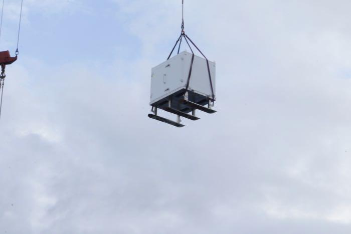 A mobile lab space is hoisted by a crane. Notice the snowboards screwed onto the bottom. They will allow it to be more easily pulled by a snowmachine across the ice floe.  