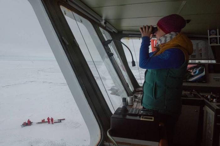 Safety engineer Bjela König watches a group of scientists from the bridge of Polarstern leaving for ice survey. (Photo: Esther Horvath; Courtesy of AWI 2019.))