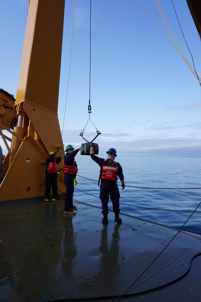 The Van Veen grab is lowered into the ocean by Coast Guard crew from the back deck of the Healy.