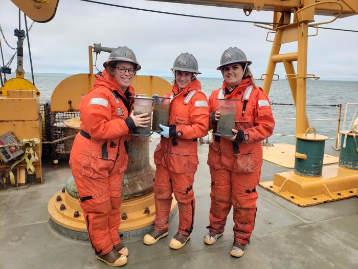 Christina Goethel, Nicole Villeneuve, and Piper Bartlett-Browne hold three sediment cores taken in the Chukchi Sea.