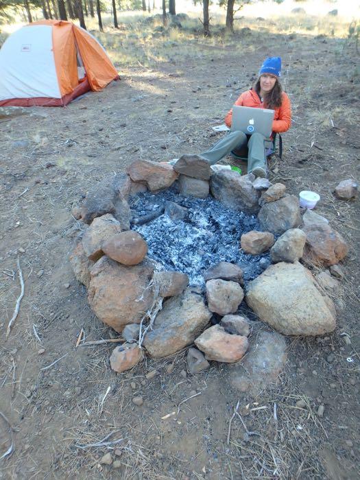 Amy Osborne does PolarTREC computer work around the campfire