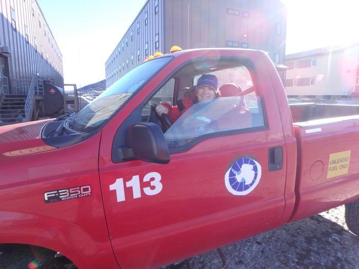 Amy Osborne in a pick up truck with the United States Antarctica program logo on the side.