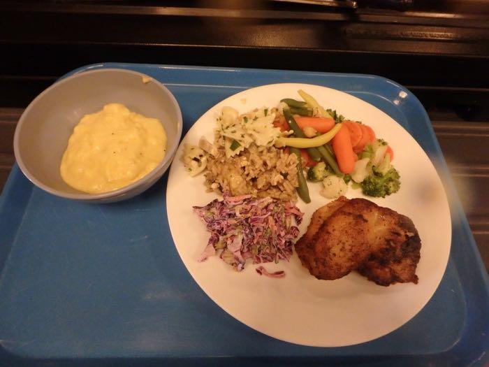 Chicken, cole slaw, grits, mixed vegetables on a plate
