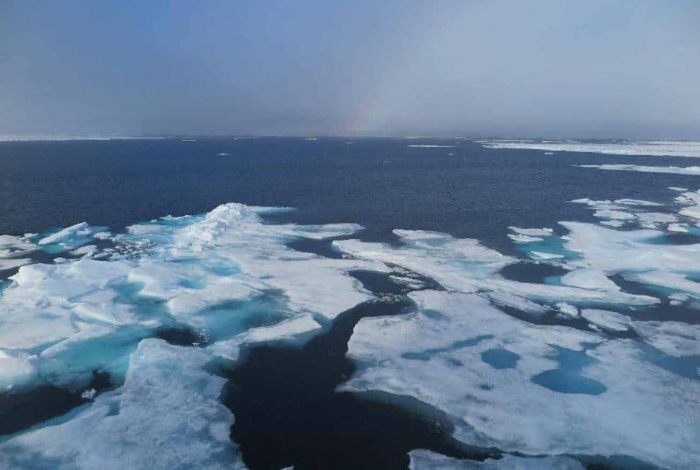 A rainbow, open water, and a few medium ice floes