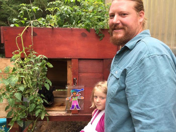 Father, daughter, and a drawing in front of a rabbit hutch