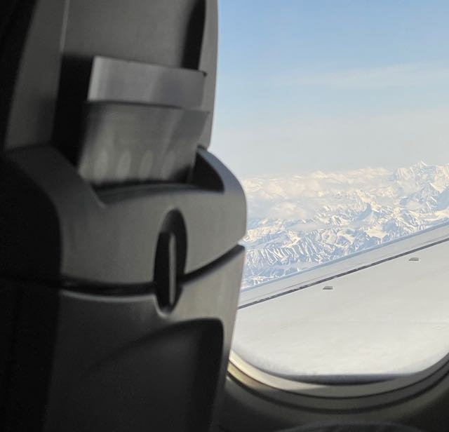 A snowy Alaskan mountain range outside a plane window. 