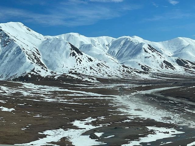 A brown landscape lined with snowy mountains. 