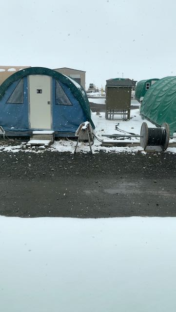 An image showing tented housing with snow coming down in front. 