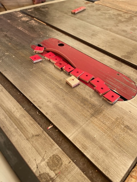 Red blocks of wood sit on top of a table saw. 