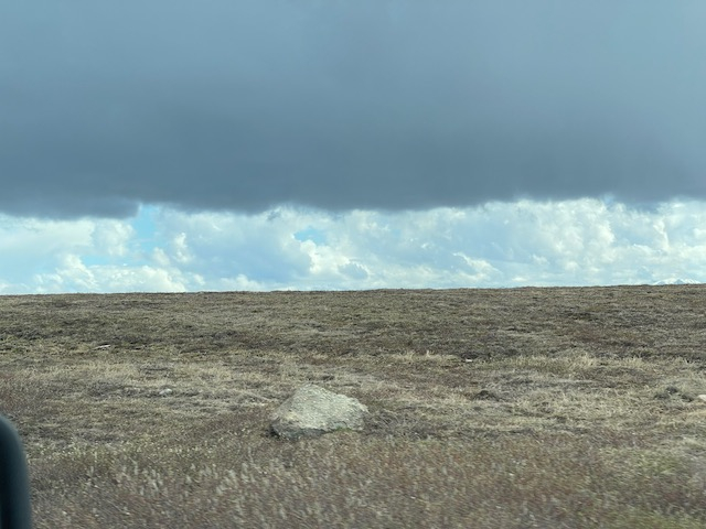 A grey cloud hangs over a brown landscape. 