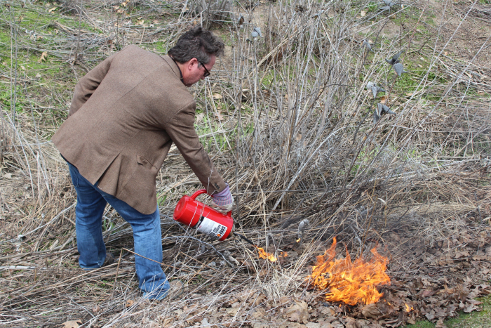 Bill Henske starting a controlled burn in student built rain garden. Photo by Ed Rich