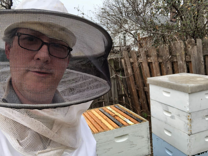 Bill Henske posing with bees from his middle school beeyard.