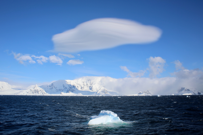 Lenticular clouds above a blue iceberg