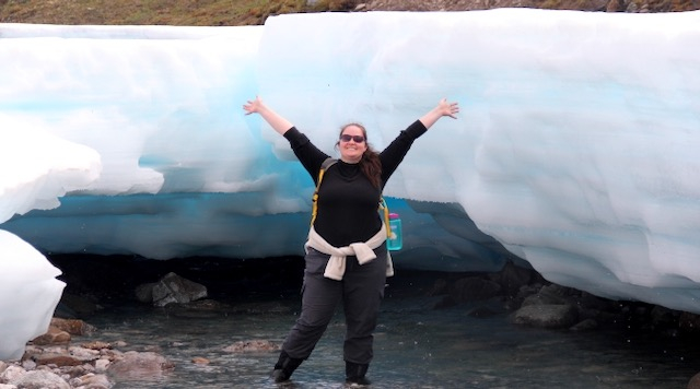 Liza Backman stands in front of layers of ice (known as Aufeis) in Alaska. 