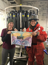 Nicole Villeneuve and Kelly Kapsar holding a flag from the Ecology Explorers program in Nome.