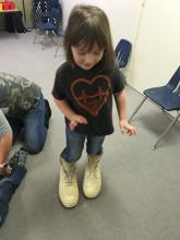 A little girl trying on big white boots
