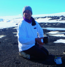 A person with a tea cup near a volcanic mountain in Antarctica
