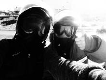 Two women in cold weather gear and snow machine helmets