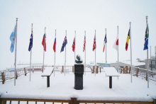 Twelve flags behind a statue in the snow