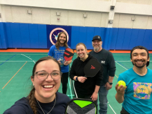 Five people standing in the South pole gymnasium with pickleball rackets