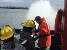 Anvil City Science Academy middle school students work the fire hose on the main deck of the R/V Sikuliaq. Photo by Lisa Seff.  September 18, 2017.