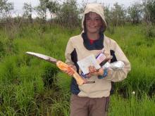 Dylan returns from soil sampling with her soil saw, field notebook, and samples.