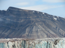 What caused the patterns and structures seen in the mountain behind the glacier?