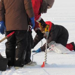 A science crew member uses an ice drill to bore a hole in the sea ice for an ice depth measurement. On the sea ice near the CCGS Louis S. St-Laurent in the Beaufort Sea. Photo by Dave Jones (PolarTREC 2017), Courtesy of ARCUS.