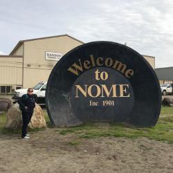 Piper Bartlett-Browne beside the Nome city sign.