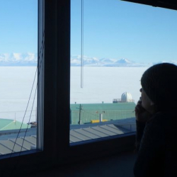 Amy looking out the window of the Crary Lab library at sea ice and mountains in the distance.