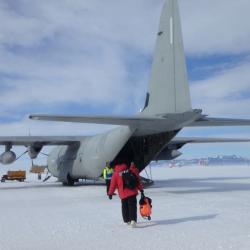 A person walks across the white ice to an airplane.