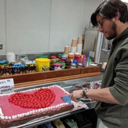 Grad student Santi Muneval cuts a piece of Valentine's Day cake