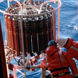 A CTD (conductivity, temperature, and depth recording instrument) being lowered into the ocean.