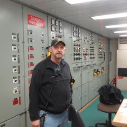 J.P. Pierce, chief engineer in front of the control panel in the engine room.